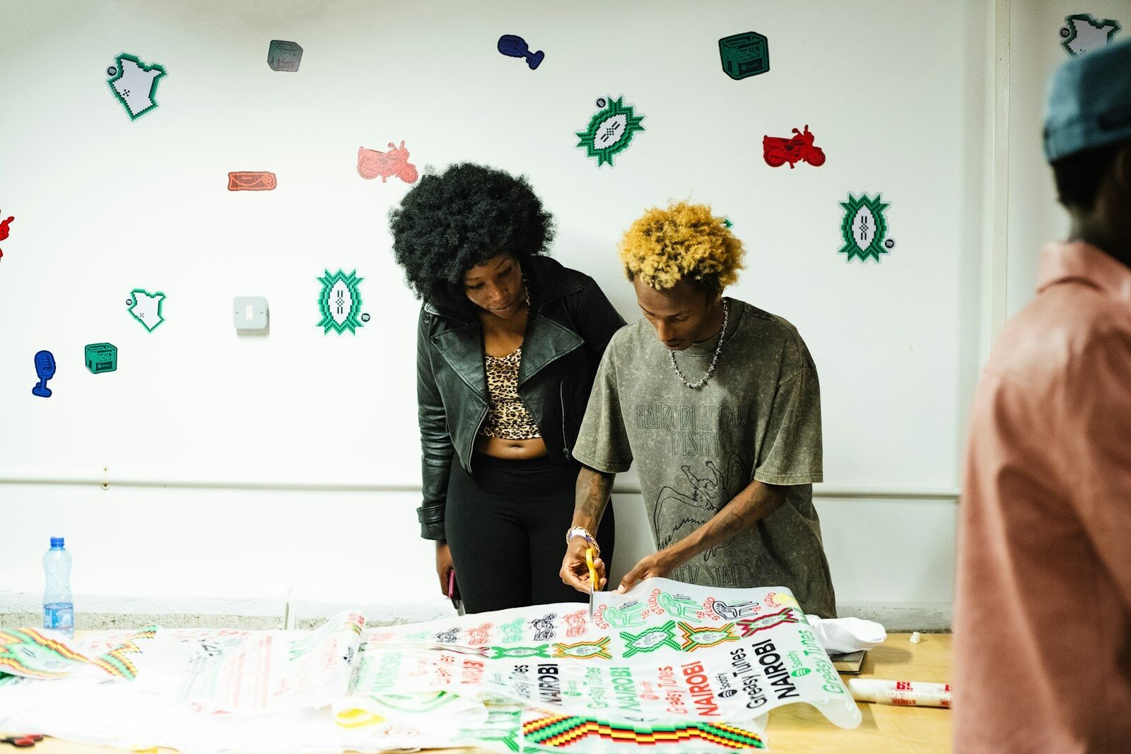 Two people working on a patterned fabric with scissors